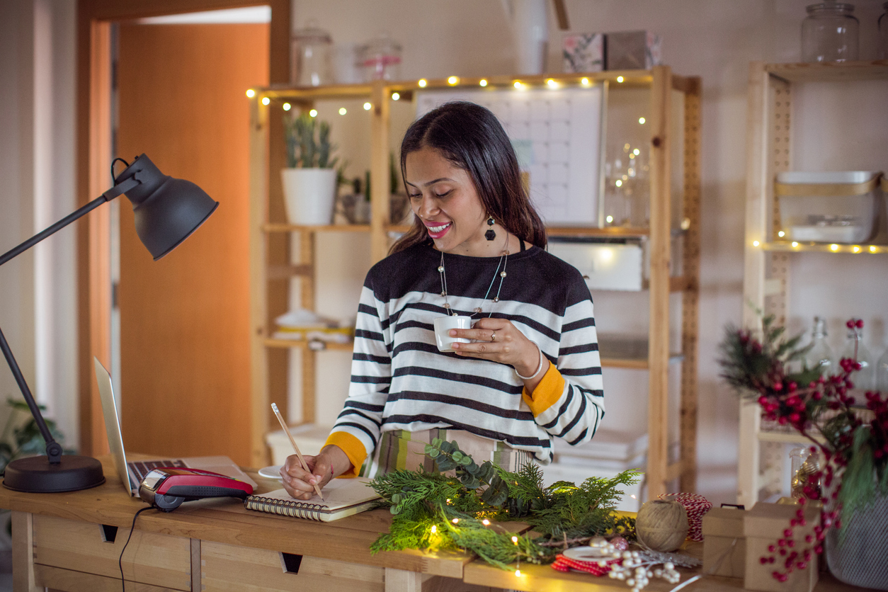lady standing in front of laptop with Christmas lights in background